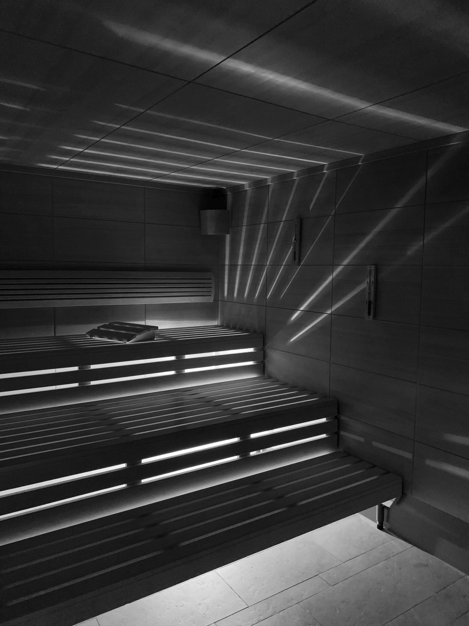 An empty sauna, light striping the benches
